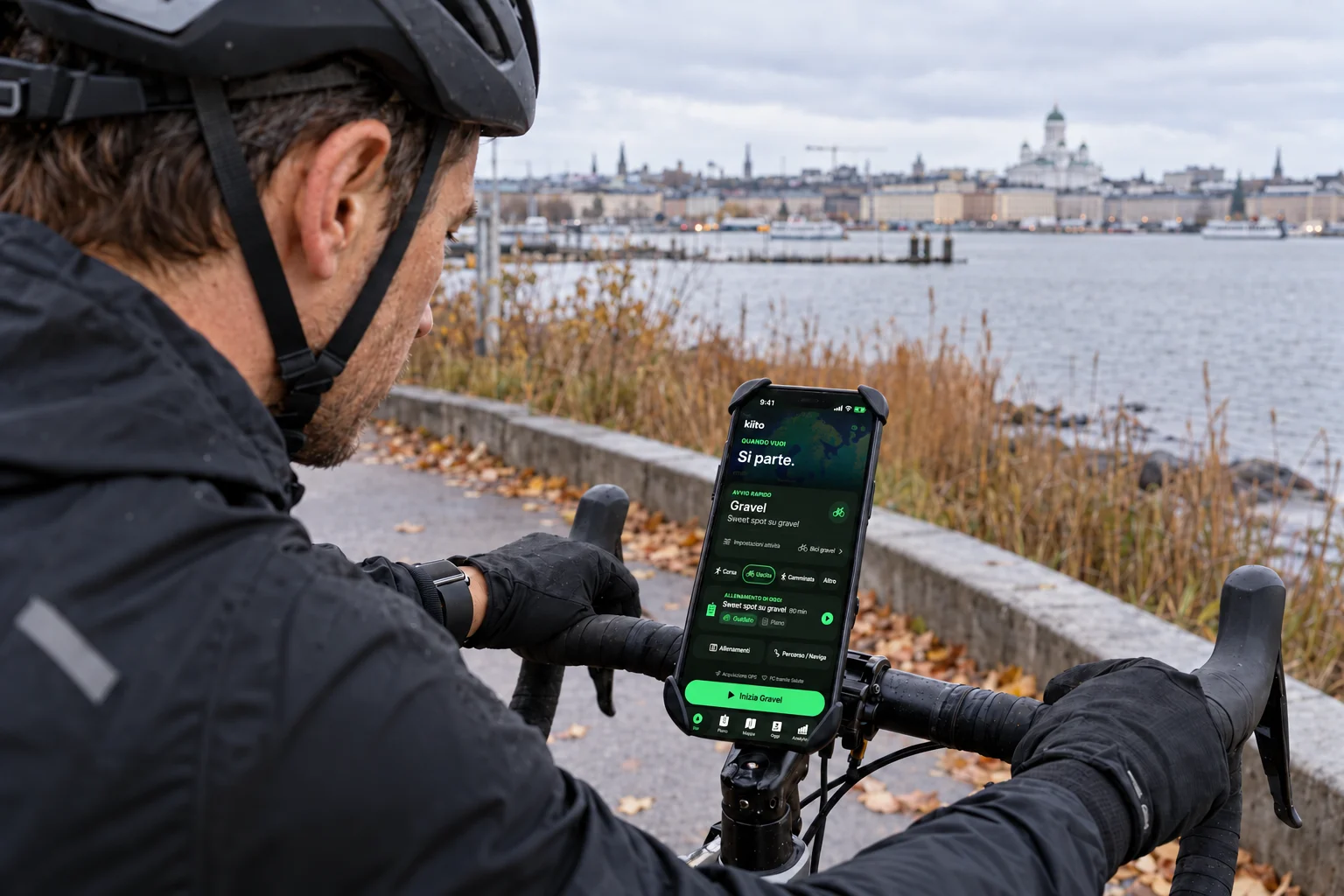 Un ciclista fermo prepara un allenamento gravel guidato in Kiito su un iPhone fissato al manubrio.