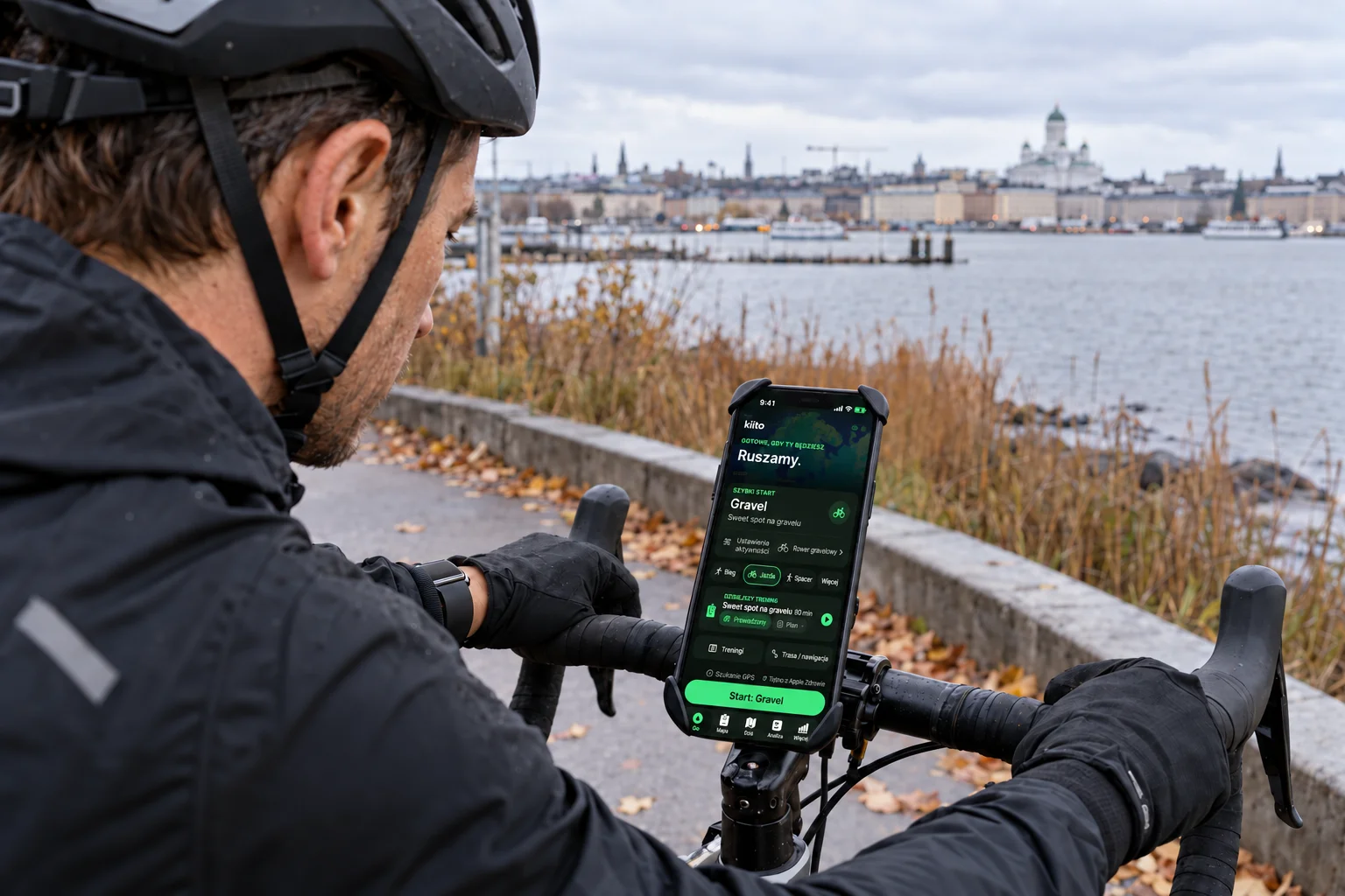 Rowerzysta podczas postoju przygotowuje trening gravelowy z prowadzeniem w Kiito na iPhonie zamocowanym do kierownicy.