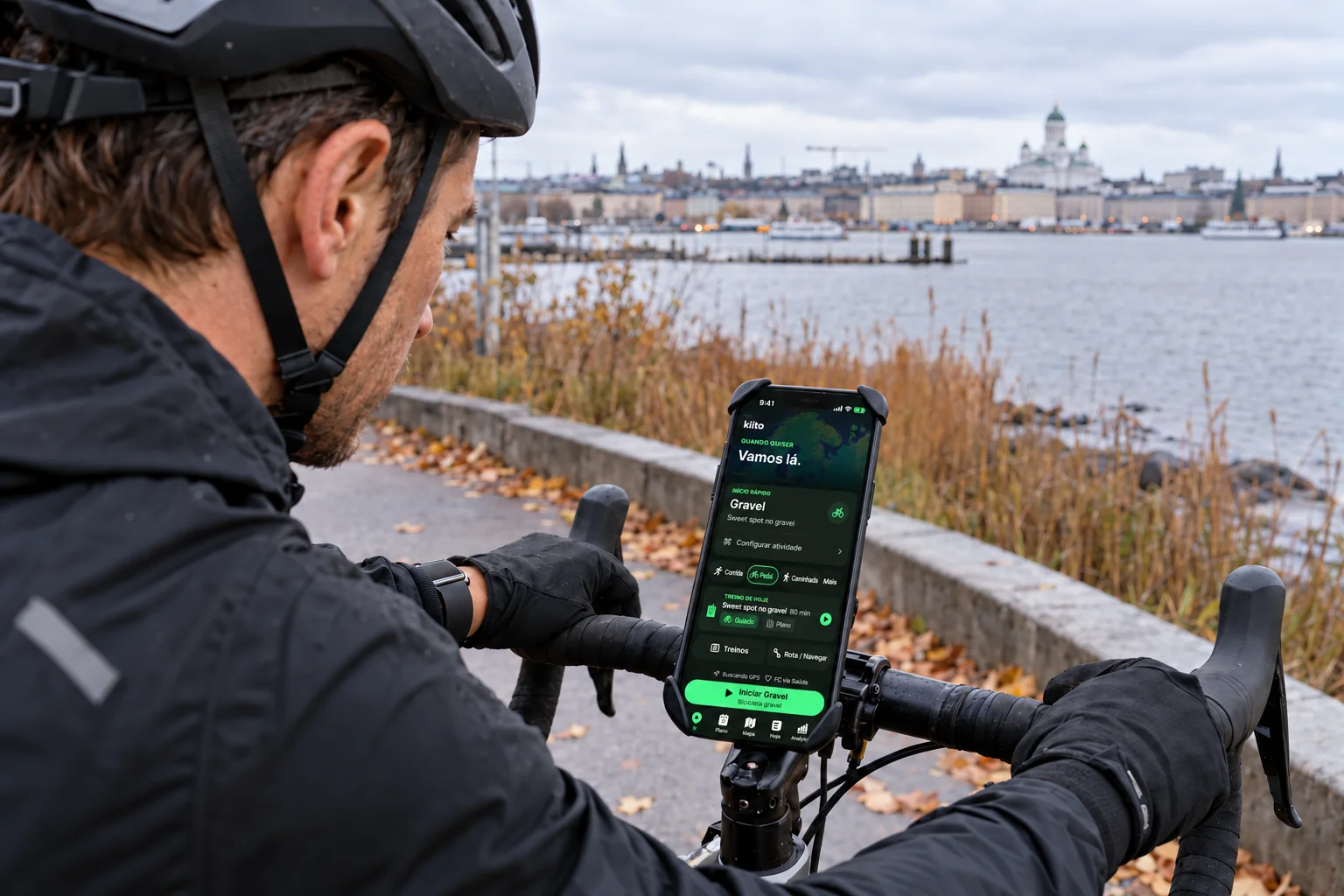 Um ciclista parado prepara um treino guiado de gravel no Kiito em um iPhone preso ao guidão.