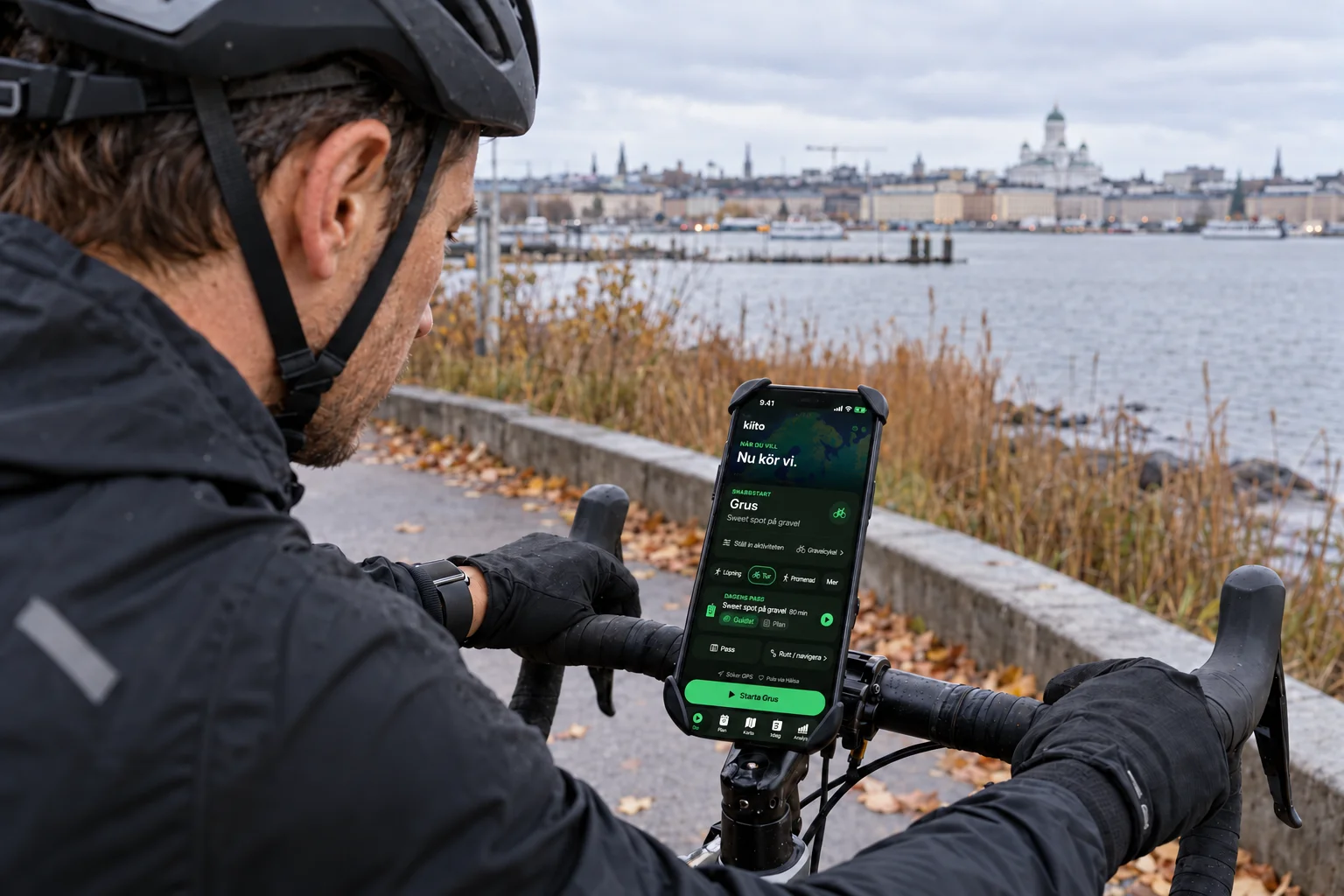 En stillastående cyklist förbereder ett guidat gravelpass i Kiito på en iPhone monterad på styret.